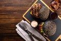 Two grilled burgers with black bun and beef cutlet, sauce and a glass of cola with ice on a wooden board, top view, copy space. Royalty Free Stock Photo
