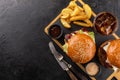 Two grilled hamburgers, French fries and a glass of cola with ice on a wooden board, ready to eat. Royalty Free Stock Photo