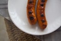 Two grilled sausages on white