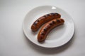 Two grilled sausages on white