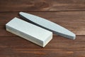 Two grindstones. Oval and rectangular double layer sharpening stone. Whetstone sharpener on wooden table background Royalty Free Stock Photo