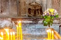 Two groups of candles in a medieval Armenian apostolic church in the foreground in defocus and a bouquet of flowers in the backgro Royalty Free Stock Photo