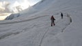 Two groups of climbers are walking in a bunch on the glacier at dawn. View from the back. Trekking from Camp 2 to Camp 1 under