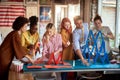 Two groups of employees making paper towers, separated in different competitive multiethnic teams