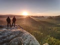 Two guys close to edge on cliff, watching awakening nature