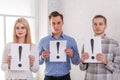 Two guys and a girl stand next to keep the sheets with exclamation marks Royalty Free Stock Photo