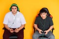 Two guys playing video games in front of yellow background Royalty Free Stock Photo