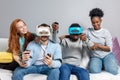 Two guys playing video games using VR glasses and girlfriends support them. Royalty Free Stock Photo