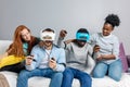 Two guys playing video games using VR glasses and girlfriends support them. Royalty Free Stock Photo