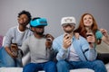 Two guys playing video games using VR glasses and girlfriends support them. Royalty Free Stock Photo