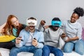 Two guys playing video games using VR glasses and girlfriends support them. Royalty Free Stock Photo