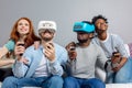 Two guys playing video games using VR glasses and girlfriends support them. Royalty Free Stock Photo