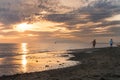 Two guys running on the beach at sunset