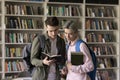 Two guys schoolmates discuss task standing in library