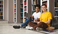 Two guys studying on floor in library, smiling at camera Royalty Free Stock Photo