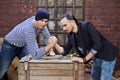 Two guys wrestle on wooden chest