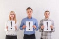 Two guys and a girl stand next to keep the sheets with exclamation marks on a gray background Royalty Free Stock Photo