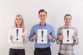 Two guys and a young girl stand next to keep sheets with exclamation marks on a gray background Royalty Free Stock Photo