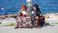 Two Gypsy women sit on the pavement of seaside