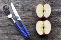 Two half apples and knife and fork on an old wooden table