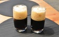 Two half full glasses of black beer on the table detail