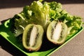 Two half juicy ripe kiwi fruit, fresh lettuce on plastic plate. Green background. Salad leaf. Organic healthy food. Detox diet Royalty Free Stock Photo