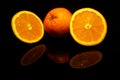 Two  half and an orange isolated on black with reflections Royalty Free Stock Photo