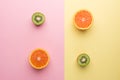 Two Half Orange and Two Half Kiwi on Geometry Yellow Pink Pastel Background, Top View. Royalty Free Stock Photo