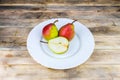 Two and half pears in white plate, rustic wooden table Royalty Free Stock Photo