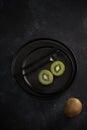 Two halfs of green kiwi on black plate. Fresh ripe fruit. Healthy food concept