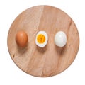 Two halfs and one unpeeled boiled eggs on wooden cutting board