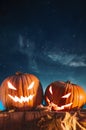 Two halloween pumpkins on fence with starry sky