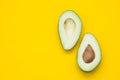 Two halves of avocado on a yellow background. Top view. Copy, empty space for text