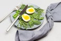 Two halves of boiled chicken egg, spinach leaves, arugula and green peas on gray ceramic plate Royalty Free Stock Photo