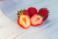 Two halves of a cut whole strawberry berry on a white wooden background Royalty Free Stock Photo