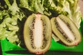 Two halves juicy ripe kiwi fruit, fresh lettuce on plate. Green background. Salad leaf. Organic healthy food. Detox diet concept. Royalty Free Stock Photo