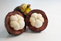 Two halves of an open mangosteen & whole fruit on white background