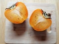 Two halves of persimmon on a desk, from above