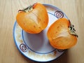 Two halves of persimmon on a plate, from above