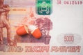 The two halves of the red pill lie on the banknote of five thousand russian rubles.