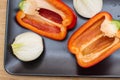 Two halves of red sweet pepper and two halves of onion on a black plate. Royalty Free Stock Photo