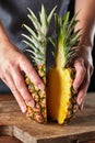 Two halves of ripe organic pineapple hold the girl`s hands on an old wooden board. Exotic fruit Royalty Free Stock Photo