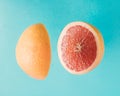 Two halves of sliced grapefruit fly in the air. Summer concept on light blue cyan background Royalty Free Stock Photo