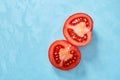 Two halves of tomato placed on blue background, top view, close-up, shallow depth of field. Royalty Free Stock Photo