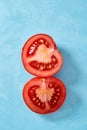 Two halves of tomato placed on blue background, top view, close-up, shallow depth of field, vertical. Royalty Free Stock Photo