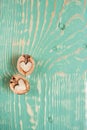 Two halves of walnut as heart are lying on light green wooden table with stripes and squiggly stains.