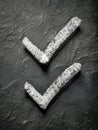 Two hand-drawn white chalk check marks on rough black textured surface symbolizing tasks completed or approval signs in concept of Royalty Free Stock Photo