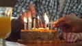 Two hand lighting candles in birthday cake
