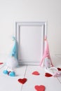 Two hand-made gnomes in love sit at a white frame on a light background Royalty Free Stock Photo