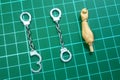 Two Handcuffs miniature with 1:12 Scale Action Figure Arm for Size Comparation on a Cutting Mat Royalty Free Stock Photo